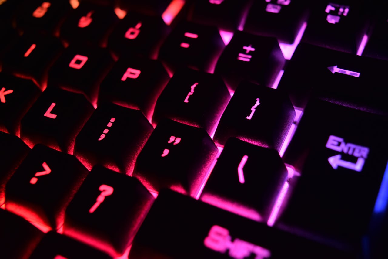 services-01 Vibrant close-up of a modern RGB backlit mechanical keyboard with glowing keys.